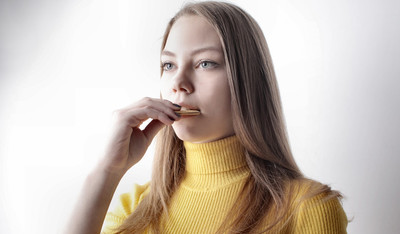 woman in yellow sweater eating while on a video conference