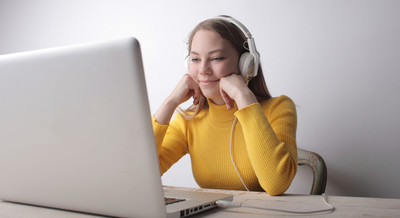 woman in yellow sweater sitting on chair in front of a laptop